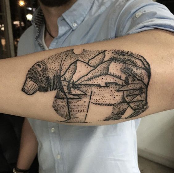 Tatuaje estilo dotwork de oso con paisaje en el antebrazo izquierdo
