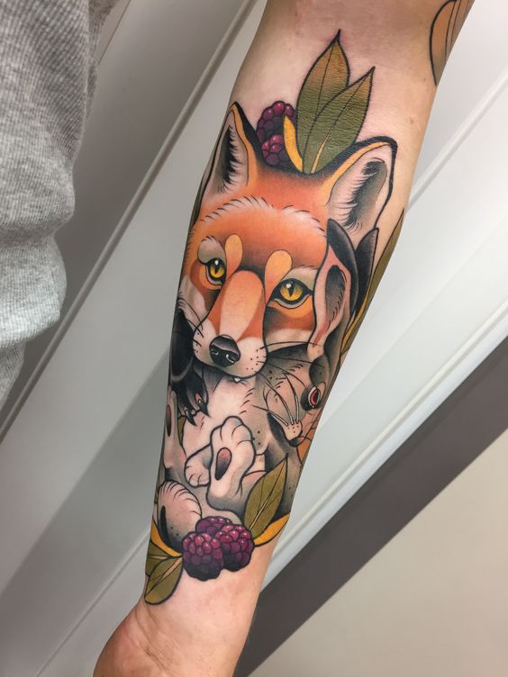 Tatuaje de zorro con conejo en la boca en el brazo izquierdo